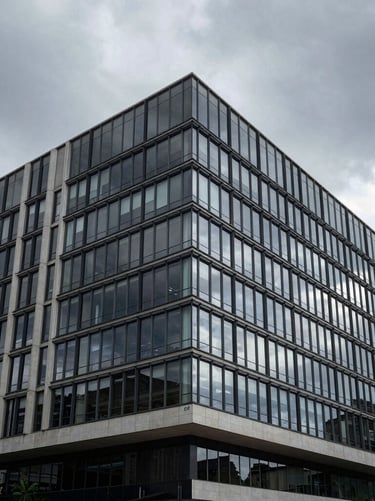A cinematic wide shot of a modern minimalist building facade in Brazil. High-contrast architectural photography showing clean lines and glass surfaces under a moody gray sky.