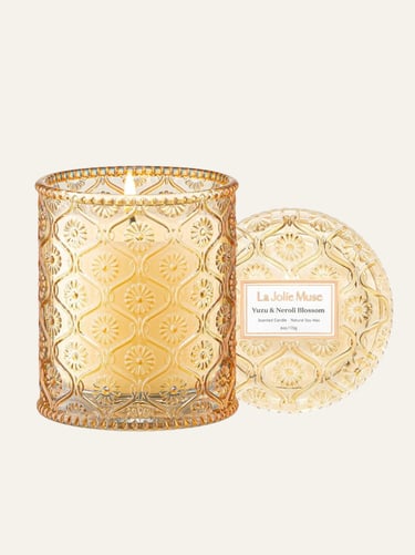 picture of La Muse Jolie peach colored glass candle jar with lid on the side