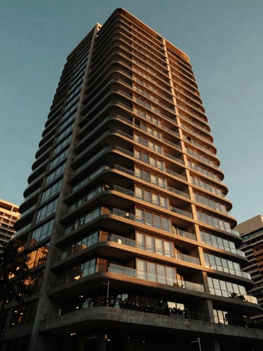 Dramatic low angle shot of a modern luxury residential skyscraper in Sydney, concrete and glass facade, warm golden hour reflection, architectural digest style.