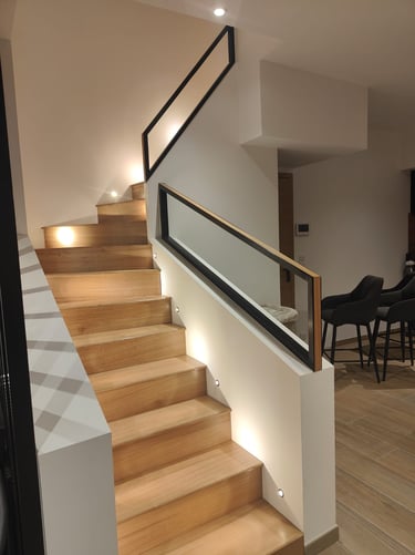 a solid oak staircase with black and oak steel railings and lights in the wall