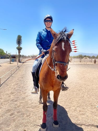 a man in a blue jacket riding a horse witn bow and arrows