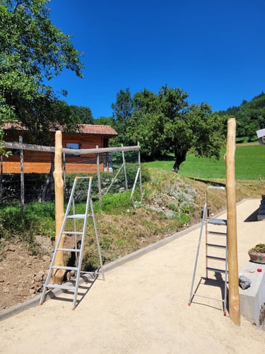 Two wooden gate posts installed near metal ladders on a new garden gravel path.