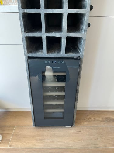 A La Sommeliere wine cooler fridge built into a gray concrete storage rack in a modern kitchen.