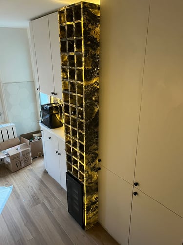 Custom backlit gold marble wine rack integrated into white modern kitchen cabinetry.