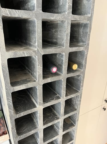 Custom gray stone wine rack with carved square slots holding two bottles.
