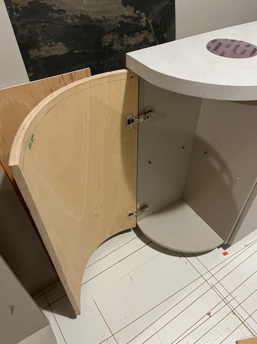 Custom curved plywood cabinet door with hidden hinges for a rounded kitchen island base.