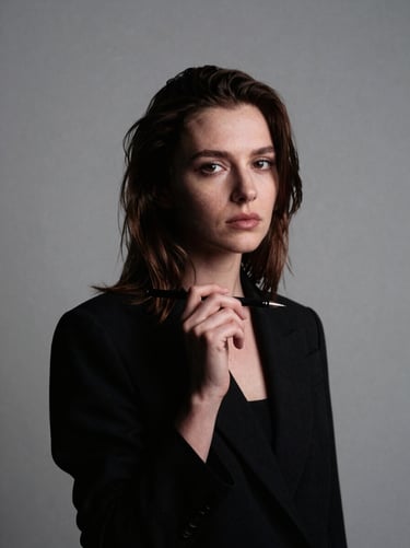 Moody editorial portrait of artist Elena Rostova holding an illustration pen, sterile minimalist studio background, high-contrast directional lighting, 35mm film