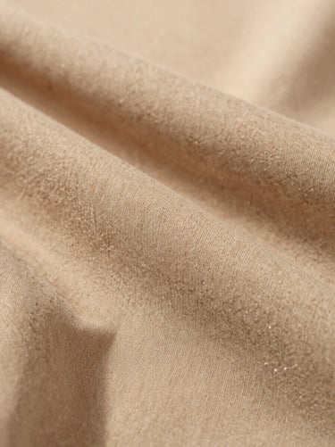 Macro close-up detail of premium breathable cotton fabric drape and fine stitching, soft natural overcast light, warm sand tones, 35mm lens