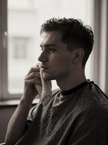 High-contrast side-lit portrait of a barber preparing a hot towel, desaturated charcoal tones, shallow depth of field, 35mm