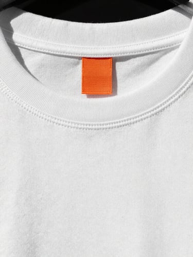 Extreme close-up of a washed white T-shirt collar showing intact high-density stitching and structured shape, direct sunlight