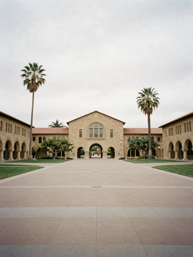 Wide environmental shot of a university quadrangle in California, historic Spanish colonial architecture, soft overcast daylight