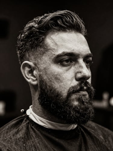 Black and white portrait of a master barber with a neat beard, low-key editorial photography, dramatic side-lighting