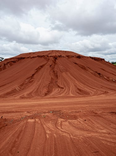 Low-angle cinematic shot of a massive leveled red clay terrain in Brasília, ready for foundation, high contrast overcast sky.