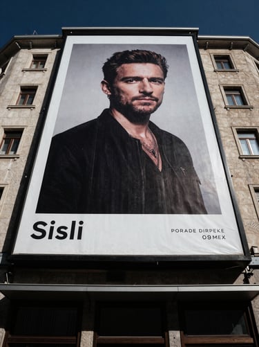 Wide-angle street view of a towering facade advertisement in Sisli, high-contrast urban tones, dramatic daylight highlighting building texture