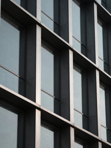 Extreme close-up of high-contrast steel and glass facade, sharp geometric lines, deep shadows, desaturated cool tones, minimalist editorial style.