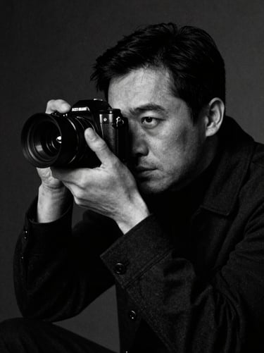 Moody black and white portrait of a male film director looking through a camera viewfinder, dramatic practical lighting, high contrast, 35mm grain