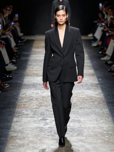 Sharp runway walk of a model in structured black tailoring, direct sunlight, sharp shadows, medium format film look