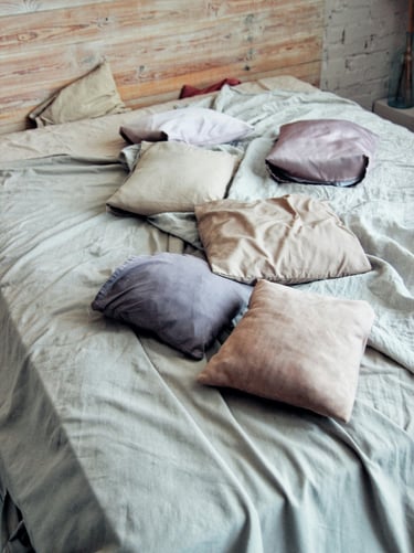 Bed with soft natural and neutral pillows in a cozy, clean interior.