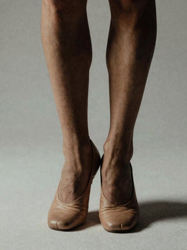 Close-up of dancer's feet in soft leather shoes, studio light highlighting muscle tone, high contrast, 35mm film grain