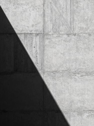 Raw concrete wall texture with geometric wooden board formwork patterns, harsh midday sun casting sharp shadows, high contrast, minimalist architectural photography