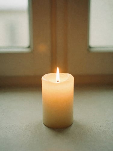 A single candle flame flickering softly in a quiet, dark room, warm golden glow, editorial photography, 35mm