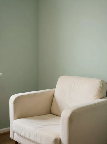 A quiet consultation room with soft natural light, warm cream chair, sage accent wall, shallow depth of field, 35mm