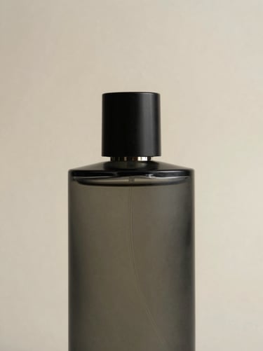 Single tall perfume bottle with a matte dark glass body, raking side light from left revealing the bottle's form against a pale parchment background, extreme close-up, clean negative space above
