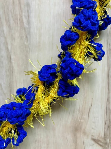 Closeup of royal blue and yellow rosebud leis twisted together