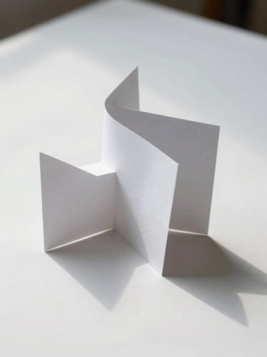 Abstract paper sculpture casting delicate geometric shadows on a clean white surface, overcast light.
