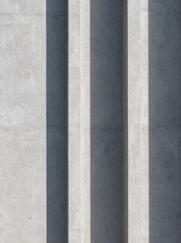 Abstract architectural shadow on a light gray concrete wall, clean vertical lines.