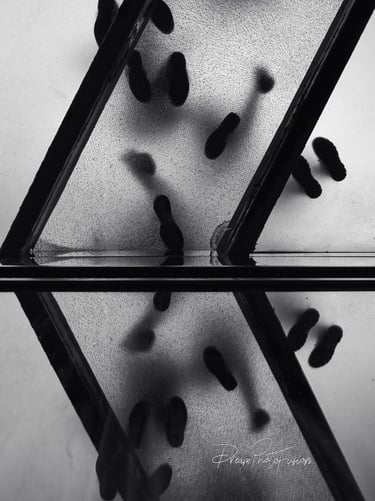 Beneath the fractured glow of a glass walkway, footsteps divide into two worlds—one real, one mirror