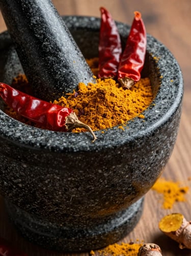 Extreme close-up of fresh spices being ground on a traditional black stone mortar, red chillies and golden turmeric powder, warm side lighting.