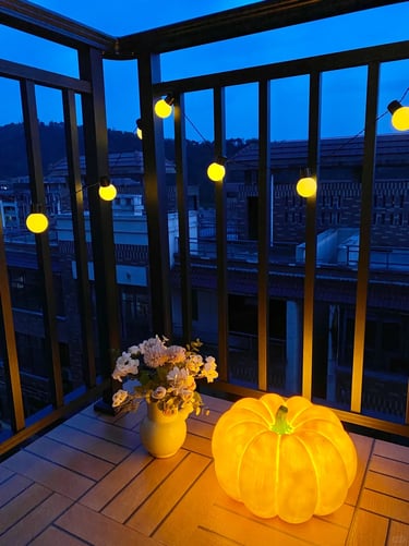 Cozy small balcony with space-saving furniture, soft cushions, potted plants, and warm evening light