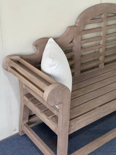 Wooden garden bench with white cushion, showing a simple and comfortable seat for a peaceful garden 