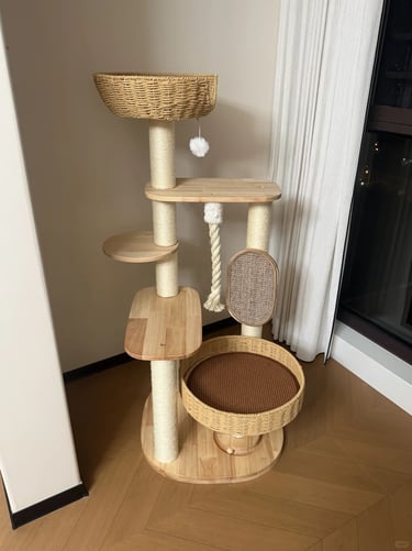 Freestanding cat tree with woven basket beds, scratching posts and wooden platforms placed beside a