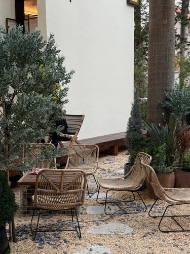 Woven outdoor chairs in a natural garden corner with gravel, plants and soft textures, creating a re