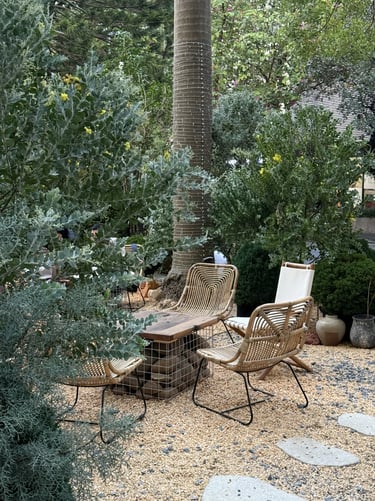 Rattan-style outdoor chairs surrounded by lush greenery, showing how woven materials add softness to