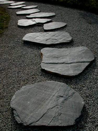Dark stone stepping path with natural slate slabs and gravel, creating a quiet and timeless garden w