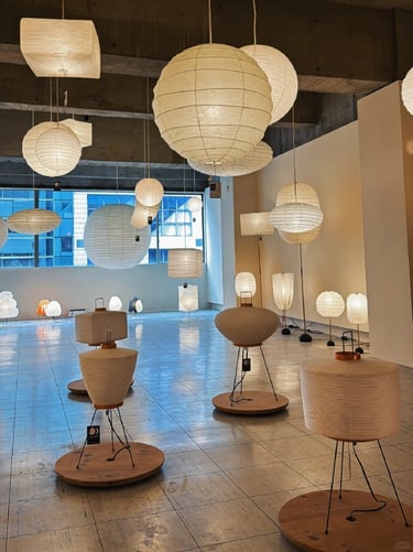 Gallery display of glowing paper lamps showing soft light, natural materials and calm modern texture