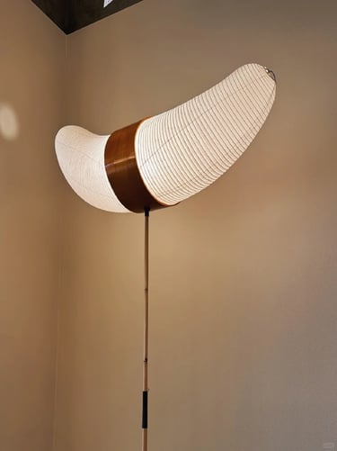 Akari-style floor lamp with curved paper shade and warm light, showing soft sculptural lighting in m