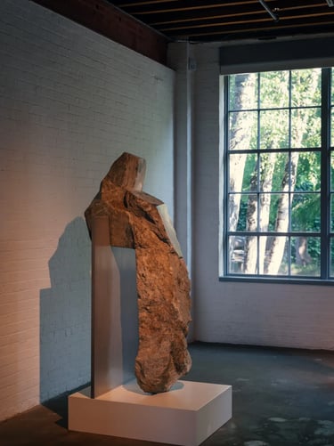 Large stone sculpture displayed beside a window, highlighting natural texture, shadow and quiet mode