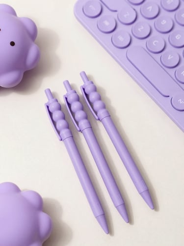 Top-down flat-lay of a cozy desk setup with lavender beadable pens, a purple keyboard, and a cute squishy, soft morning light, 35mm