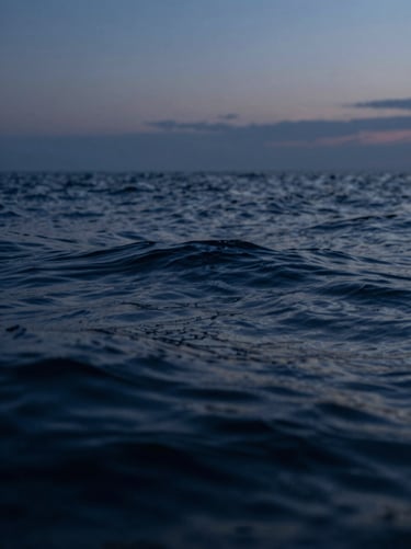 Abstract close-up of deep ocean water ripples under twilight sky, dark indigo tones, serene and silent.