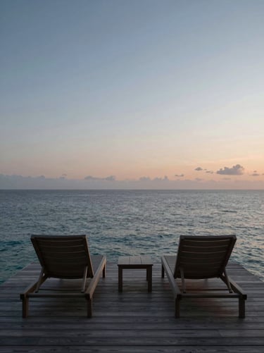 Minimalist overwater villa deck with two lounge chairs facing the infinite empty ocean at dusk