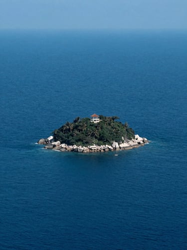 Zenith view of a tiny private island surrounded by deep blue ocean water, absolute isolation