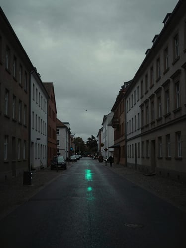 Moody overcast city street in Germany, desaturated tones with a subtle neon cyan reflection, low-key lighting cinematic