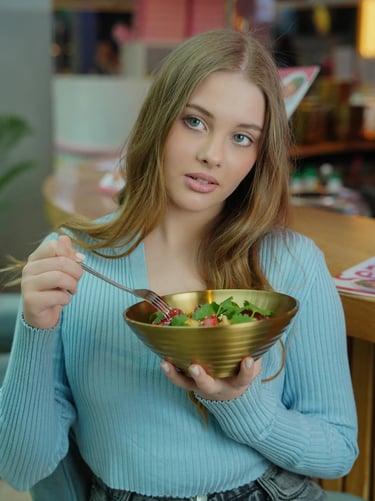 a woman in a blue sweater holding a bowl of salad
