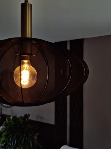 Un luminaire allumé en tissus noir devant un mur composé de panneaux décoratifs