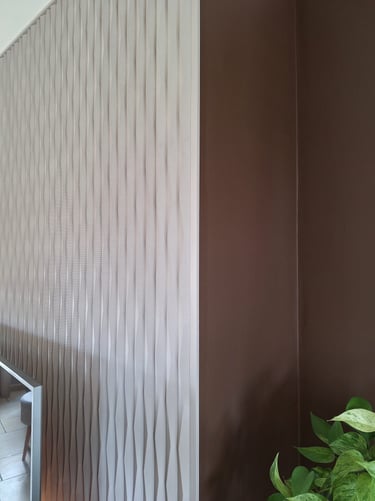 Un zoom sur des panneaux décoratifs en relief beige derrière une télévision
