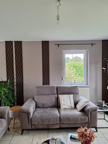 Réalisation d'un living avec des panneaux décoratifs bruns sur un mur beige avec un canapé